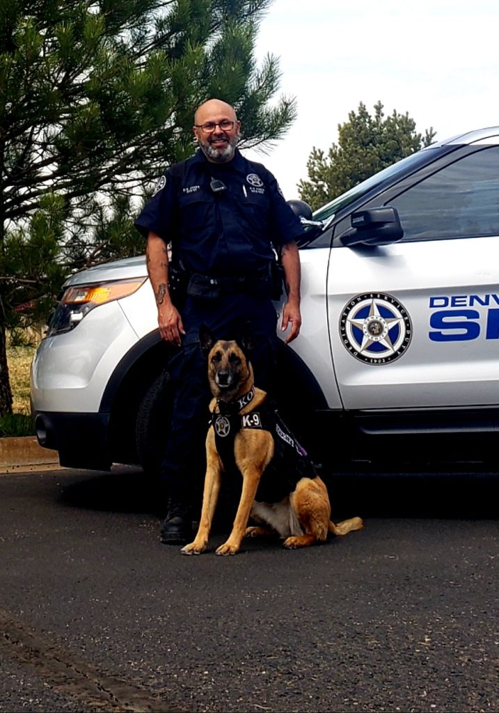 Handler kneeling beside a K9 unit dog.